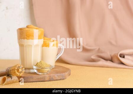 Glas und Tasse schmackhaften dalgona hojicha Latte, Chasen mit Pulver auf dem Tisch Stockfoto