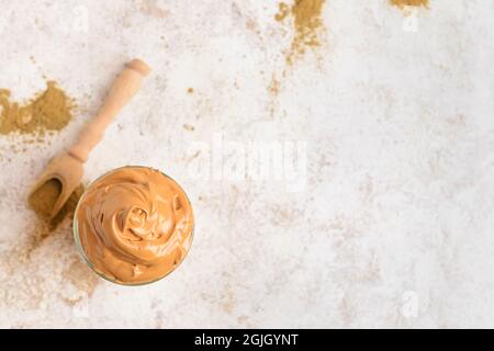 Ein Glas leckeren dalgona hojicha Latte und Pulver auf hellem Hintergrund Stockfoto