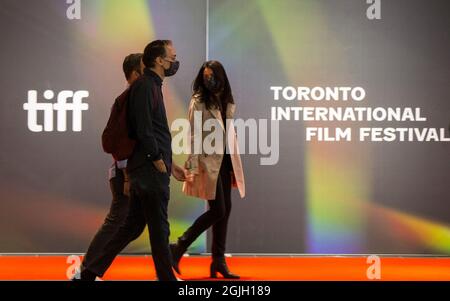 Toronto, Kanada. September 2021. Menschen mit Gesichtsmasken gehen am 9. September 2021 an einer Wand mit dem TIFF-Logo im TIFF Bell Lightbox-Hauptquartier des Toronto International Film Festival (TIFF) 2021 in Toronto, Kanada, vorbei. Das TIFF startete hier am Donnerstag und bot Vorführungen in Innenräumen, Drive-ins, Open-Air-Kinos und Online-Kinos an. Quelle: Zou Zheng/Xinhua/Alamy Live News Stockfoto