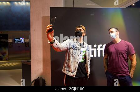 Toronto, Kanada. September 2021. Menschen mit Gesichtsmasken machen am 9. September 2021 ein Selfie im TIFF Bell Lightbox-Hauptquartier des Toronto International Film Festival (TIFF) 2021 in Toronto, Kanada. Das TIFF startete hier am Donnerstag und bot Vorführungen in Innenräumen, Drive-ins, Open-Air-Kinos und Online-Kinos an. Quelle: Zou Zheng/Xinhua/Alamy Live News Stockfoto