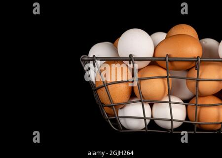 Ein kleiner Korb mit frischen, braunen und weißen Eiern während des Sonnenaufgangs, der bei einer traditionellen Bauerngemeinschaft gesammelt wurde. Stockfoto