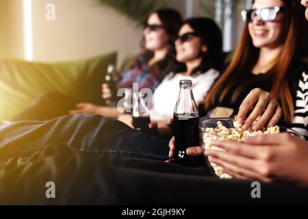 Eine Gruppe von Menschen schaut sich einen Film an. Freundinnen essen Popcorn und trinken Limonade Stockfoto