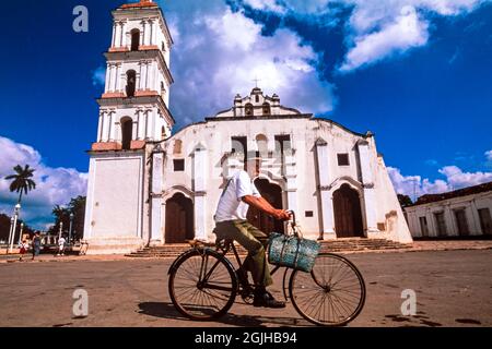 Mann auf dem Fahrrad vor der Pfarrkirche San Juan Bautista de Los Remedios, Remedios, Kuba Stockfoto