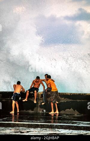 Junge kubanische Jungen spielen im Spray auf der Meereswand von Malecon, Havanna, Kuba Stockfoto