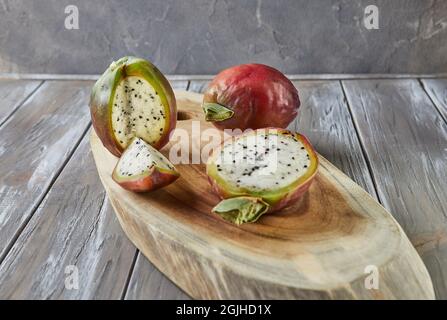 Peruanische Apfelkaktus Früchte ganz und auf Holzständer auf grauem Brett geschnitten. Wissenschaftlicher Name Cereus repandus. Stockfoto