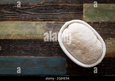 Brotteig in einem Rattankorb auf einem Tisch aus Holz Stockfoto