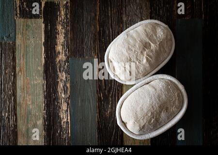 Brotteig in einem Rattankorb auf einem Tisch aus Holz Stockfoto