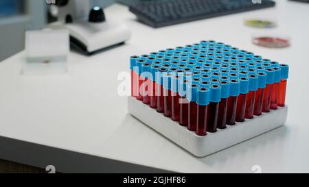 Nahaufnahme des Tabletts mit Vakuurinen und Blut auf dem Schreibtisch im Wissenschaftslabor. Chemische Glasröhrchen mit roter Lösung oder dna-Flüssigkeit in der genetischen Forschung. Medizinische Geräte für Tests Stockfoto