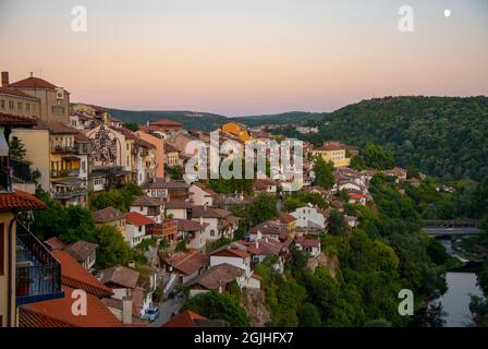 Bulgarien, Veliko Tarnovo, August 2021. Häuser mit roten Ziegeldächern, auf einem Berg vor dem Hintergrund eines sanften Sonnenuntergangs gebaut. Veliko Tarnovo in Stockfoto