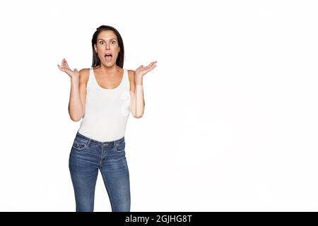 Schöne überrascht Frau auf isolierten weichen Hintergrund Blick auf die Kamera. Frau in Jeans und weißem ärmellosem T-Shirt. Hochwertige Fotos Stockfoto