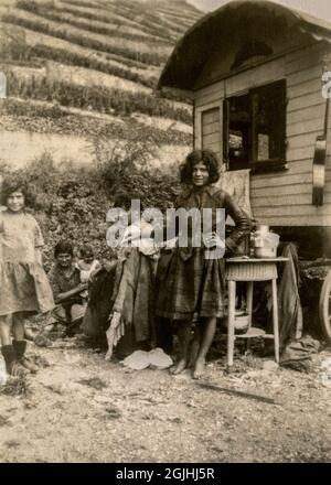 Eine Zigeuner- oder Roma-Familie in Deutschland oder Frankreich in den späten 1920er oder frühen 1930er Jahren, neben ihrer traditionellen Holzkarawane und mit einem Hang, der mit Weinreihen im Hintergrund kultiviert wurde. Lächelnd und scheinbar sorglos vor dem Zweiten Weltkrieg und rigorose Durchsetzung der Anti-Zigeuner-Gesetzgebung durch das Nazi-Regime. Vintage-Foto. Stockfoto