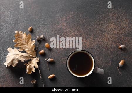 Trendiger Eichelkaffee ohne Koffein auf braunem Hintergrund mit abfallend Eichenlaub. Blick von oben. Platz für Text. Ersatzkaffee. Stockfoto