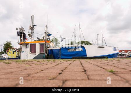 Ein wunderschönes, weiß-blaues Fischerboot, das im Hafen von Darłowo an der Ostsee festgemacht ist Stockfoto