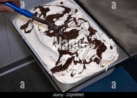 Italienische handwerkliche Eiscreme (Gelato) Herstellung. Produktionsprozess im Labor. Ein Mann, der Eiscreme in einem Tablett aus Edelstahl zubereitet. Hausgemachtes bisc Stockfoto