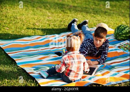 Familie verbringt Zeit zusammen. Bruder mit Schwester malen im Freien in Picknickdecke. Stockfoto