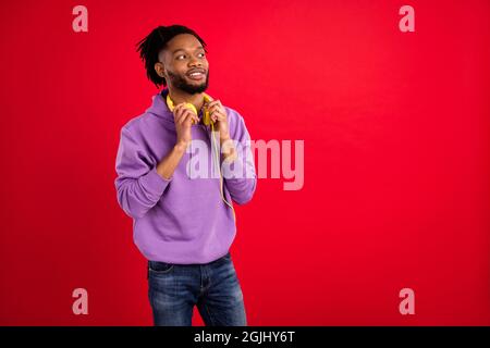 Foto Porträt Mann mit Dreadlocks tragen Kopfhörer suchen Copyspace isoliert lebendige rote Farbe Hintergrund Stockfoto