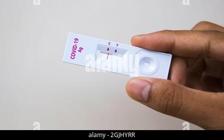 COVID-19-Tests (Rapid Antigen Test), Eine Hand mit einem COVID-Testkit, die ein negatives Ergebnis zeigt (nicht infiziert). Es ist eine Selbstprüfung Stockfoto