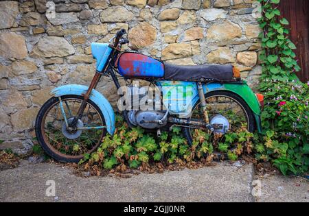 Altes rostiges und buntes Motorrad, verlassen auf der Straße Stockfoto