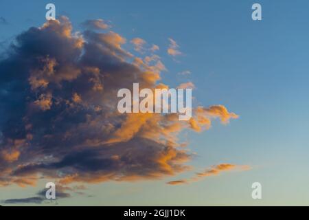 Sonnenuntergang. Schwere schwarze Cumuluswolke reflektiert gelbe Strahlen der untergehenden Sonne. Stockfoto