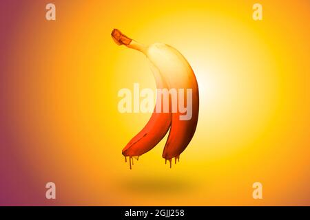 Banane auf einem hell erleuchteten orangefarbenen Hintergrund mit einer tropfenden Schokolade Stockfoto