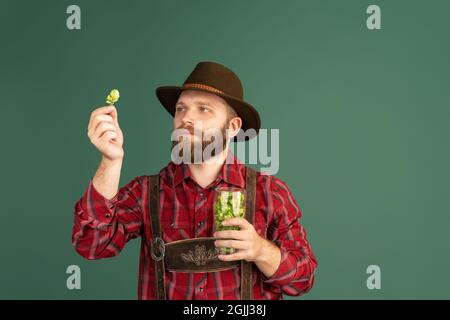 Porträt eines bärtigen Mannes, Bierbrauers in traditioneller bayerischer Tracht, der Biergläser mit wildem heißem, isoliertem Hintergrund hält. Stockfoto