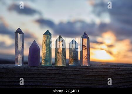 Heilende Reiki Kristalle auf Holz mit Meer bei Sonnenuntergang Hintergrund. Heilende Steine am Meer. Stockfoto