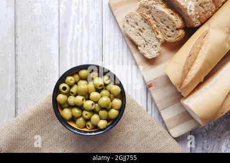 Braunes Brot und eine Schüssel mit Oliven auf dem Tisch Stockfoto