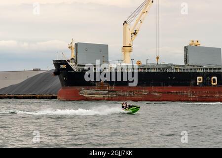 Toronto, Ontario, Kanada - 31 2021. Juli: Mann und Frau auf einem grünen Jetski vor dem Frachter am Lake Ontario. Stockfoto