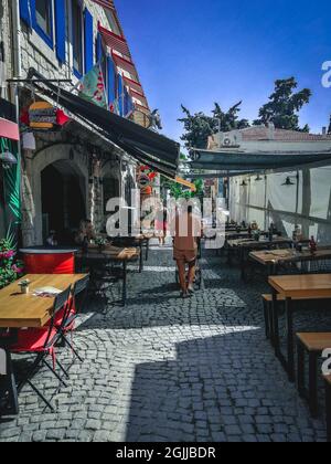 IZMIR, TÜRKEI - 15. Aug 2021: Eine schöne schmale Straße mit Café im Freien in Izmir, Türkei Stockfoto