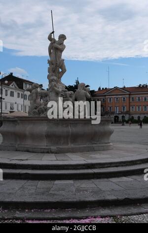 Gorizia, Italien - 25. Mai 2021: Piazza della Vittoria. Fontana del Nettuno (Neptunbrunnen) und Präfektur Görz. Friaul Julisch Venetien. Bewölkt Stockfoto