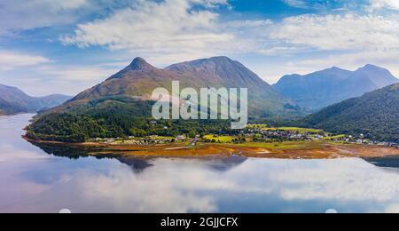 Luftaufnahme von der Drohne von Sgorr na Ciche oder dem Pap von Glencoe und dem Dorf Invercoe (links) und Glencoe Dorf neben Loch Leven in Glen Coe, Loch Stockfoto