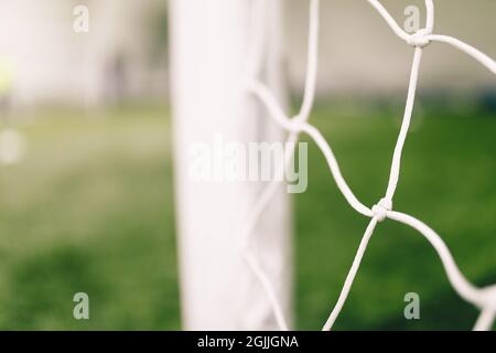 Fußballhintergrund. Fußballausrüstung. Weißes Fußballnetz auf einem Tor. Fußball-Netzknoten. Verschwommener Torpfosten im Hintergrund Stockfoto