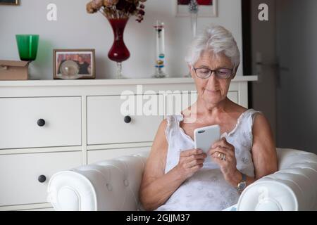 Porträt einer älteren Frau, die eine SMS auf ihr Mobiltelefon schreibt Stockfoto