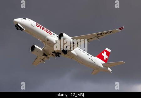 Swiss International Air Lines Airbus A220-300 (REG: HB-JCR) nimmt mit dunklen Wolken im Hintergrund ab. Stockfoto