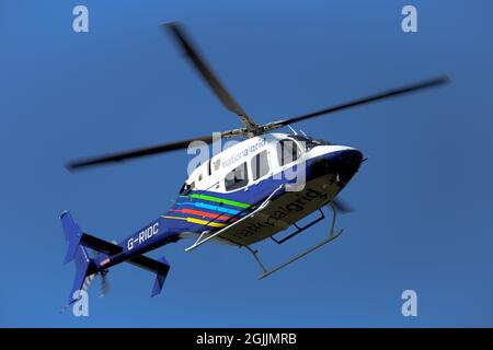 Ein nationaler Hubschrauber schwebt über einem Mast, während die Besatzung Hochspannungsleitungen über North East Derbyshire untersucht. Stockfoto