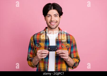 Foto von charismatischen ziemlich jungen Gentleman tragen kariertes Outfit halten Kreditkarte lächelnd isoliert rosa Farbe Hintergrund Stockfoto