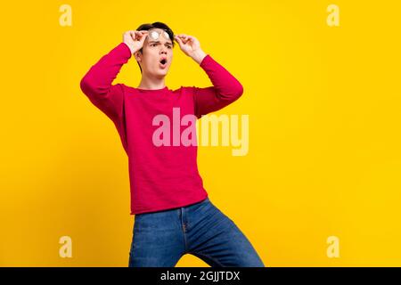 Foto von beeindruckt Brunet jungen Kerl suchen leeren Raum tragen roten Pullover auf gelbem Hintergrund isoliert Stockfoto