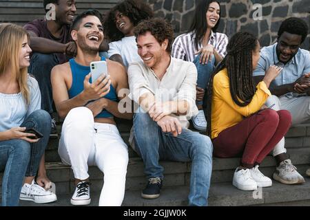 Junge multirassische Gruppe von Freunden mit dem mobilen Smartphone auf der Treppe sitzen - Jugend Millennial Lifestyle-Konzept Stockfoto