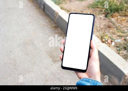Mockup Bild der Frau halten weißen Desktop-Bildschirm Handy im Freien. Verschwommene Asphaltstraße im Hintergrund. Stockfoto