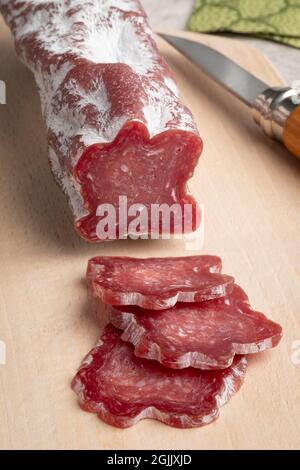 In Scheiben geschnittene Saint Agaune-Wurst, ein französischer getrockneter Schweinefleischkochisson, auf einem Schneidebrett Stockfoto