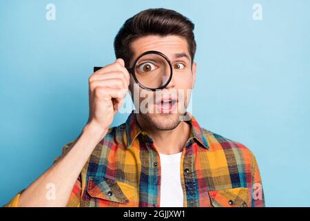 Portrait von attraktiven funky Kerl halten in der Hand vergrößern Glas suchen Lösung isoliert über helle blaue Farbe Hintergrund Stockfoto
