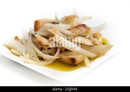 'Chocos aliñado', ein typisch spanisches Essen, Tintenfisch in Streifen mit Zwiebeln. Platte auf Weiß isoliert Stockfoto