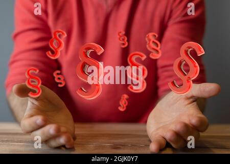 Nahaufnahme der konzeptionellen Zeichen von Recht und Gerechtigkeit über den Händen eines Mannes in einem roten Hemd Stockfoto