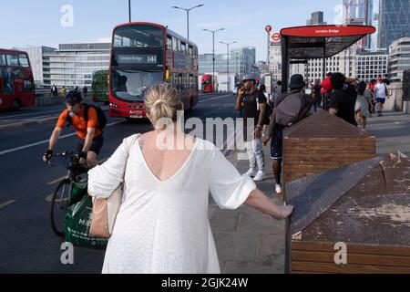 In der Woche, in der nach der Pandemie von Covid und den Sommerferien viele weitere Londoner an ihre Büroarbeitsplätze zurückkehrten, wartet eine Frau auf einen Bus, während Pendler und öffentliche Verkehrsmittel am südlichen Ende der London Bridge in Southwark am 8. September 2021 in London ihren Weg nach Süden machen. England. Stockfoto