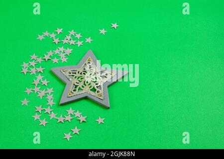 Grauer Stern aus Holz und Metall mit kleinem Glitzer auf grünem Hintergrund Stockfoto