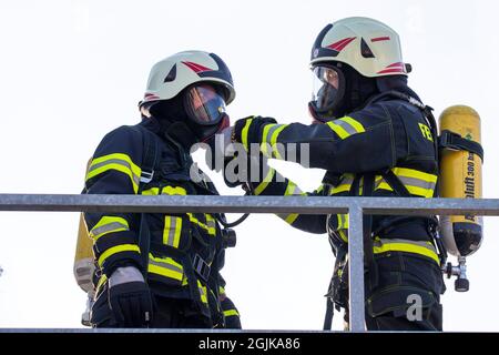 Pirna, Deutschland. September 2021. Zwei Feuerwehrmänner bereiten sich vor, indem sie die Sauerstoffleitung der anderen auf der Schutzmaske überprüfen. Feuerwehren aus dem Landkreis Sächsische Schweiz-Osterzgebirge über Szenarien im Feuertrainingscontainer. Quelle: Daniel Schäfer/dpa-Zentralbild/Daniel Schäfer/dpa/Alamy Live News Stockfoto