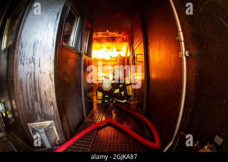 Pirna, Deutschland. September 2021. Zwei Feuerwehrleute bereiten sich im Behälter auf einen Überschlag vor, der gelöscht werden muss. Feuerwehren aus dem Landkreis Sächsische Schweiz-Osterzgebirge zu Szenarien im Feuerwehrtrainingsbehälter. Fisheye shot Quelle: Daniel Schäfer/dpa-Zentralbild/Daniel Schäfer/dpa/Alamy Live News Stockfoto