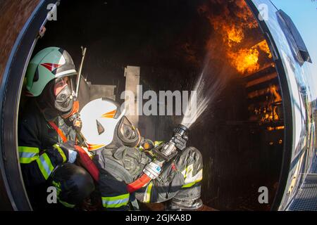 Pirna, Deutschland. September 2021. Zwei Feuerwehrleute bereiten sich im Behälter auf einen Überschlag vor, der gelöscht werden muss. Feuerwehren aus dem Landkreis Sächsische Schweiz-Osterzgebirge zu Szenarien im Feuerwehrtrainingsbehälter. Fisheye shot Quelle: Daniel Schäfer/dpa-Zentralbild/Daniel Schäfer/dpa/Alamy Live News Stockfoto