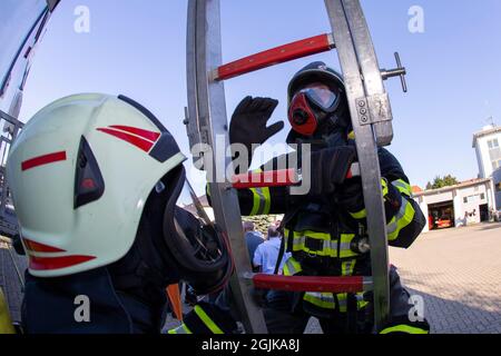 Pirna, Deutschland. September 2021. Ein Feuerwehrmann klettert die Leiter hinauf, um loszulegen. Feuerwehren aus dem Landkreis Sächsische Schweiz-Osterzgebirge zu Szenarien im Feuertrainingscontainer. Fisheye shot Quelle: Daniel Schäfer/dpa-Zentralbild/Daniel Schäfer/dpa/Alamy Live News Stockfoto