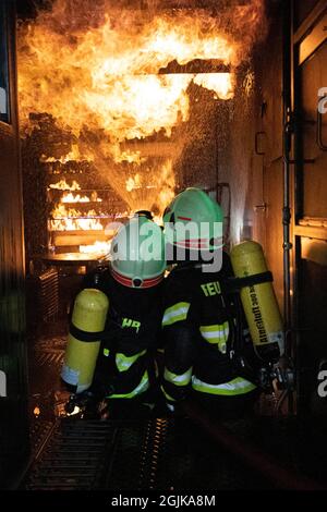 Pirna, Deutschland. September 2021. Zwei Feuerwehrleute bereiten sich im Behälter auf einen Überschlag vor, der gelöscht werden muss. Feuerwehren aus dem Landkreis Sächsische Schweiz-Osterzgebirge zu Szenarien im Feuertrainingscontainer. Quelle: Daniel Schäfer/dpa-Zentralbild/Daniel Schäfer/dpa/Alamy Live News Stockfoto